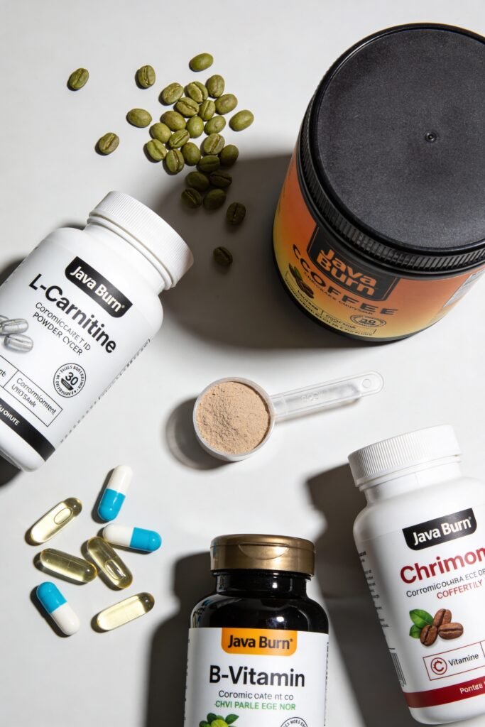 A clean, styled flat lay arrangement showing: green coffee beans, small transparent capsules or scoop of L-Carnitine powder, chromium pills, B-vitamin bottles, and a jar of Java Burn. Coffee beans scattered around. Natural light from above. On a clean white or light gray surface. Professional product photography, top-down 90-degree angle.