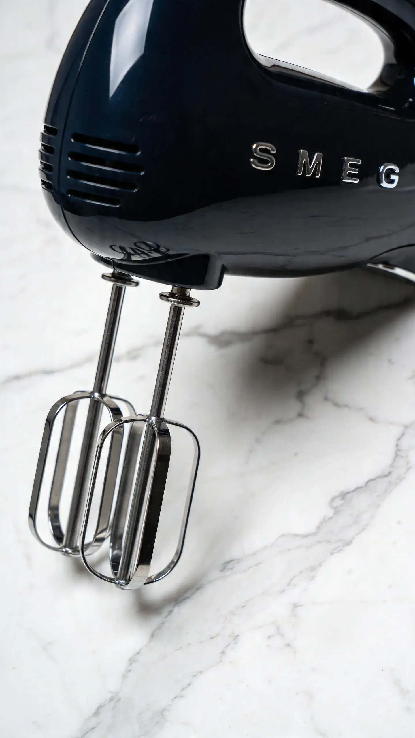 matte black Smeg HMF01BLEU hand mixer closeup on marble